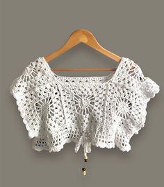 a white crocheted top hanging on a wooden hanger