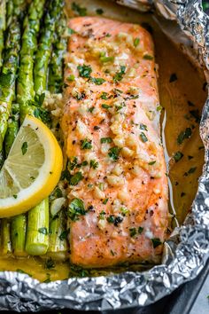 salmon and asparagus in foil with lemon wedges on the side for garnish