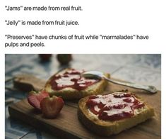 two pieces of bread with jam on them and strawberries in the middle, sitting on a cutting board