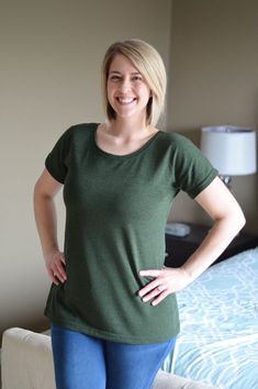 a woman standing in front of a bed with her hands on her hips and looking at the camera