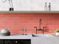 a kitchen with pink brick walls and white counter tops, black cabinets and brass faucets