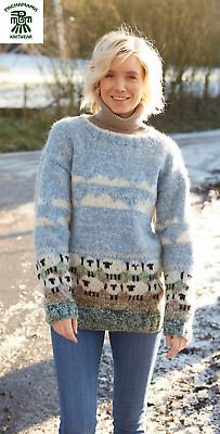 a woman standing on the side of a road wearing a blue and white knitted sweater