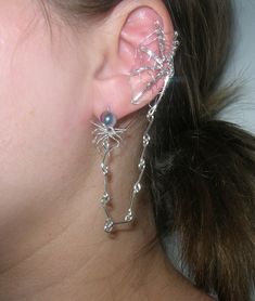 A beautiful spider web ear cuff with a connected spider earring! It hangs on the outside of whichever ear you want and can be bent to fit anyone's size of ear. If you want a pair pick quantity as two. The wire is silver plated with a two color toned glass bead for the spider! A made to order piece just in time for Halloween! You'll be able to customize this with different color beads and kinds of wire.  Note: If you want the spider to just dangle and not go into the earlobe. Just message me with your order and I will customize that for you! Thank you! Silver Punk Jewelry For Cosplay, Gothic Silver Jewelry For Cosplay, Silver Gothic Jewelry For Cosplay, Witchy Jewelry For Halloween Festival, Handmade Gothic Body Jewelry For Party, Silver Metal Jewelry For Cosplay, Witchy Metal Jewelry For Parties, Silver Earrings For Halloween Festival, Halloween Silver Body Jewelry Gift