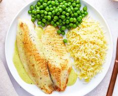 a white plate topped with fish, rice and peas