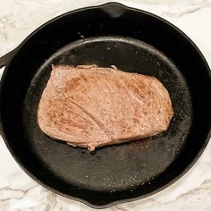 a piece of meat is cooking in a skillet