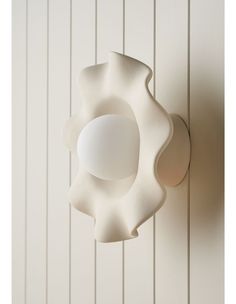 a white light fixture mounted on the side of a wall next to a wood paneled wall