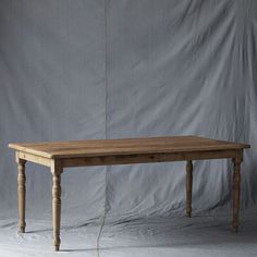 a wooden table sitting on top of a white floor next to a gray wall in front of a grey backdrop