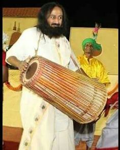 a man with a long beard holding a large drum in front of two other men