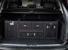 the back end of a black car with its trunk open and two drawers in it