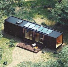 an aerial view of a small cabin in the middle of some trees and grass,