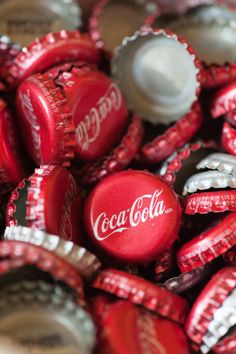 a pile of coca - cola bottle caps sitting on top of each other in red and white