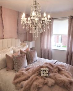 a chandelier hangs from the ceiling above a bed in a bedroom with pink walls