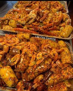 two trays filled with cooked shrimp and corn on the cob next to each other