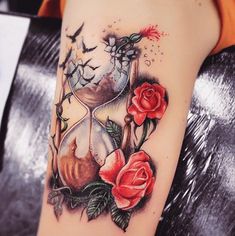 a woman's arm with roses and an hourglass tattoo on her left forearm