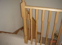 a wooden banister next to a white carpeted floor