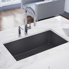 a kitchen sink sitting under a faucet next to a white counter top in a living room