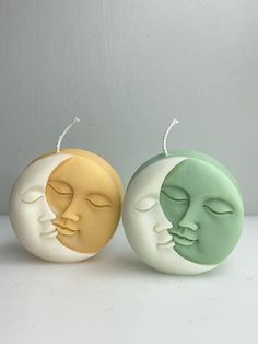 two soaps with faces on them sitting next to each other in front of a white wall