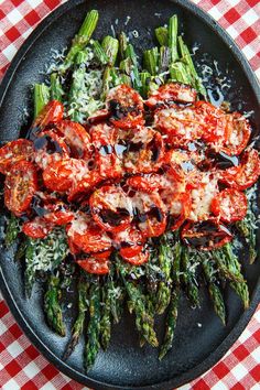 asparagus with tomatoes and parmesan cheese in a skillet on a checkered tablecloth