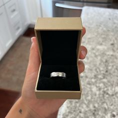 a person holding an open box with a ring in it's left hand on a counter top