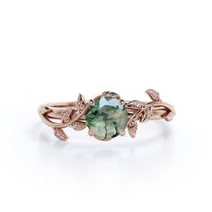 a ring with an oval green stone surrounded by leaves and diamonds on the band, set in 18k rose gold