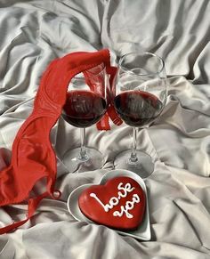 two glasses of wine and a heart shaped box with the word love spelled on it