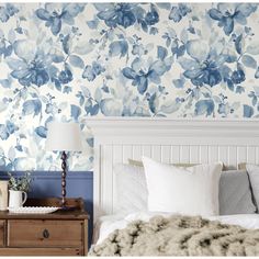 a bedroom with blue flowers on the wall and white bedding, along with two nightstands