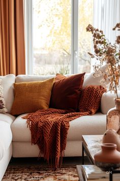 a living room with a white couch and orange throw pillows on the back of it