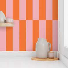 an orange and pink striped wallpaper in a kitchen with a white counter top next to a vase