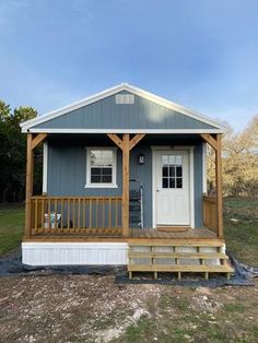 a small blue house with a porch and stairs