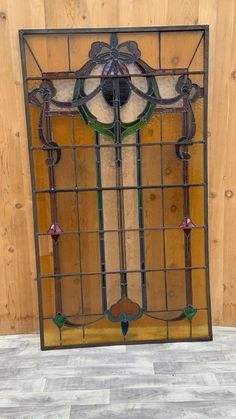 an old stained glass window on the side of a wooden wall