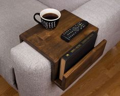 a cup of coffee sitting on top of a wooden table next to a remote control