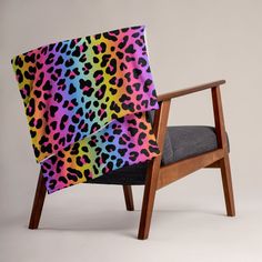 a chair with a colorful leopard print blanket on it's back and seat cushion