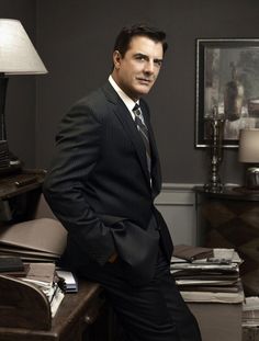 a man in a suit leaning on a desk