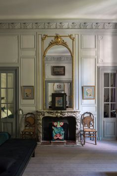 a living room filled with furniture and a fire place in front of a wall mounted mirror