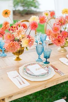 a wooden table topped with plates and vases filled with colorful flowers on top of it