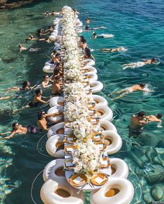 people swimming in the water with plates and flowers on them