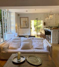 a living room filled with lots of furniture and a kitchen in the backround