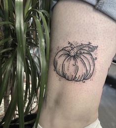 a small black and white pumpkin tattoo on the leg