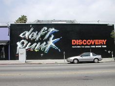 a car parked in front of a black building with graffiti on it's side