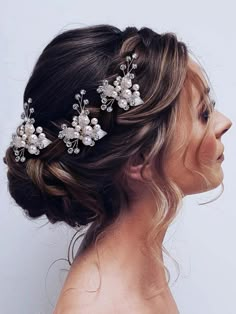 a woman wearing a bridal hair comb with pearls and flowers on it's head