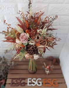 a vase filled with lots of flowers sitting on top of a wooden table next to a sign