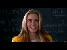 a woman standing in front of a blackboard with writing on it and smiling at the camera