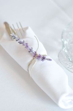 the napkin is tied with twine and has lavender flowers on it, along with a silver fork