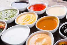 many different sauces are in small white bowls