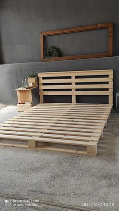 a wooden bed frame sitting on top of cement floor next to a planter and window