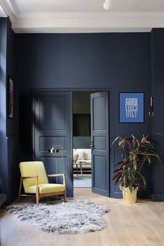 a living room with blue walls and wooden floors, a yellow chair in the foreground