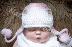 a newborn baby wearing a white knitted hat and scarf