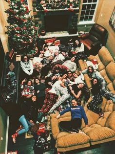 a group of people laying on top of couches in front of a christmas tree