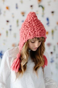 a woman wearing a pink knitted hat with tassels