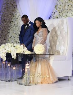 two people standing next to each other in front of a table with flowers and candles